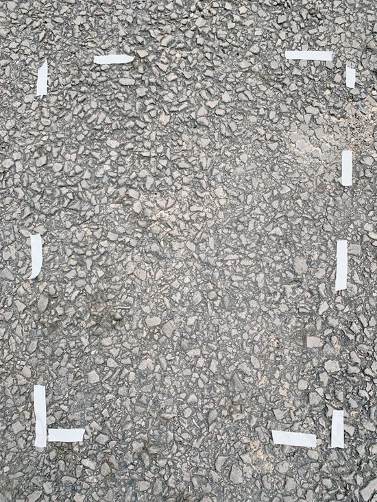 Photo of asphalt road with pieces of white tape outlining the section of gravel that exactly matches the section of gravel in Hayden Shirley's long-dead chicken photo.